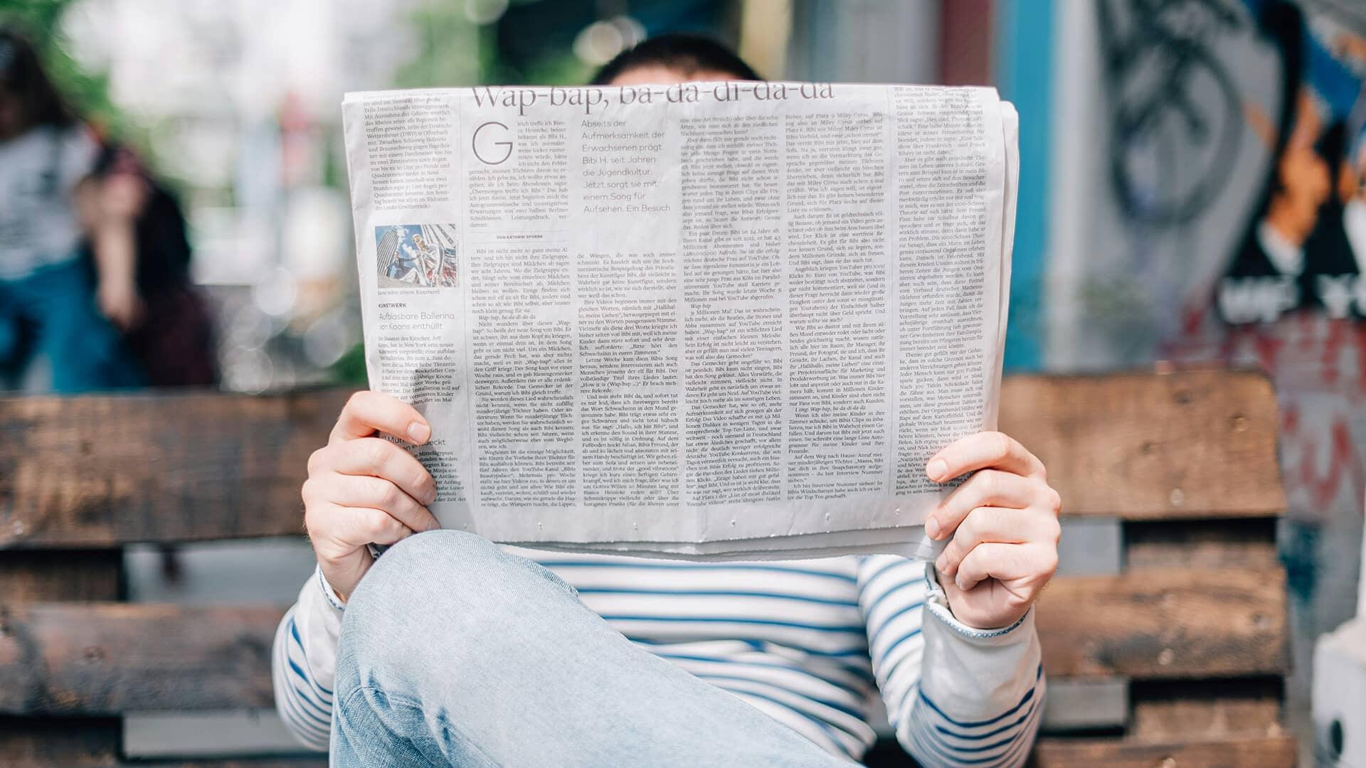 Un homme sur un banc qui lit un journal
